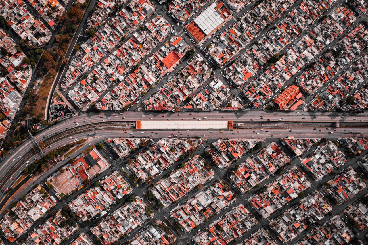 High-angle aerial view of a densely populated cityscape with a central highway.