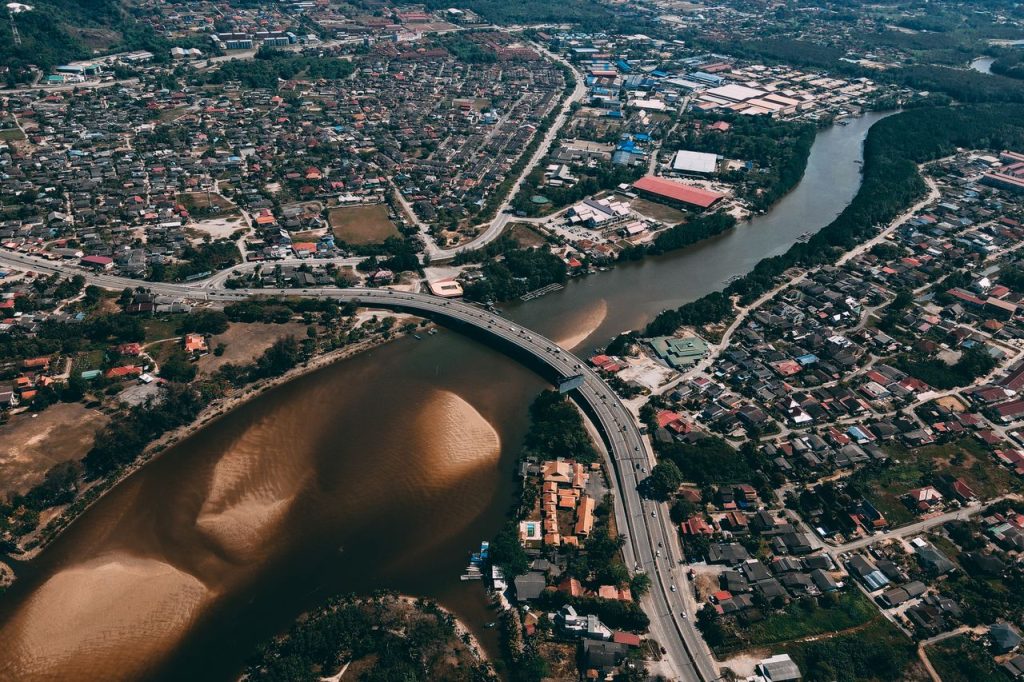 High-altitude urban cityscape featuring a winding river and highway bridge.