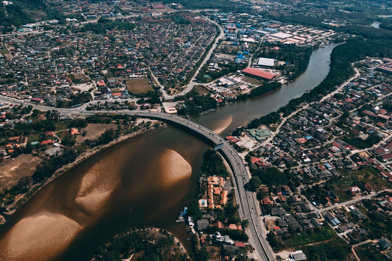 High-altitude urban cityscape featuring a winding river and highway bridge.